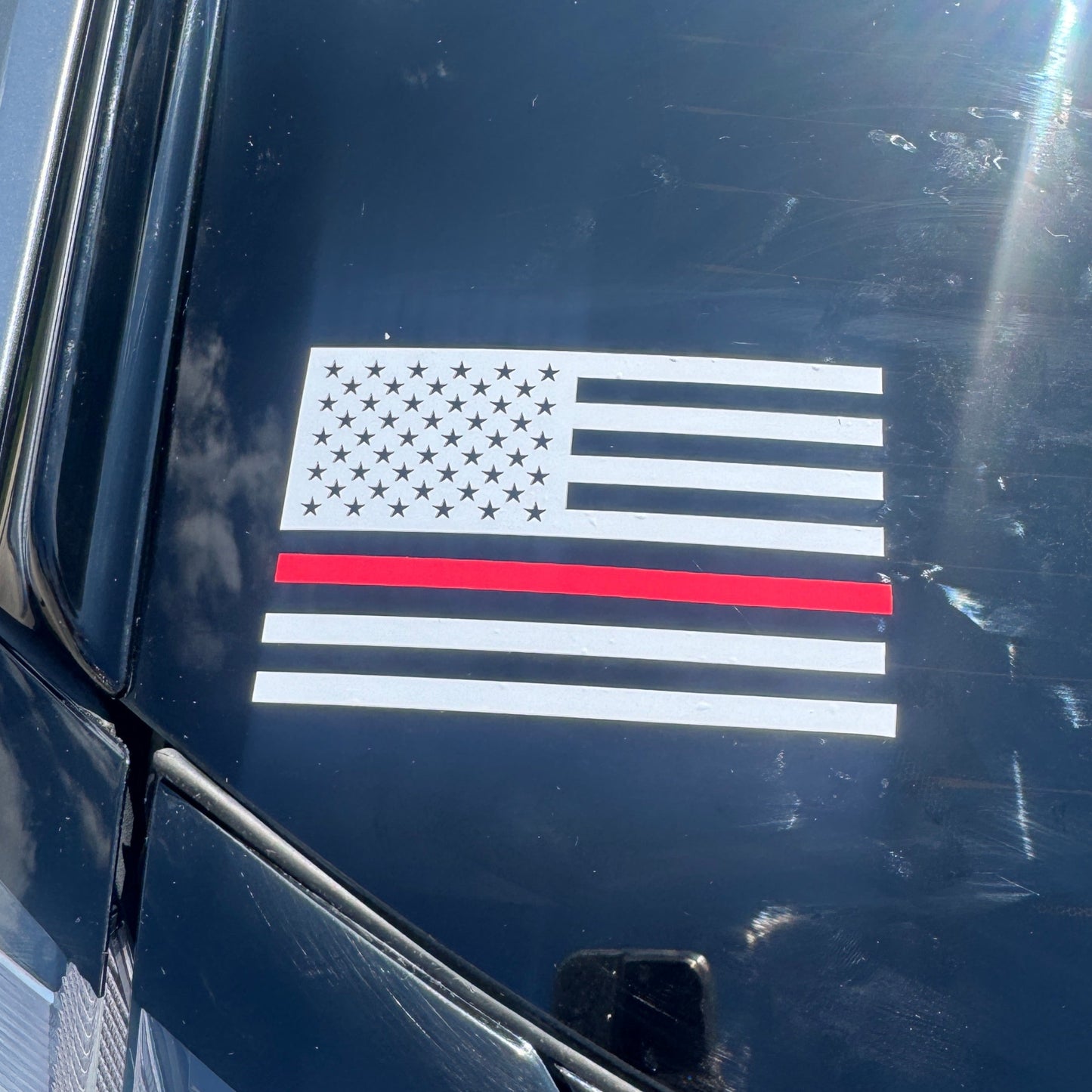 American flag decal with a red stripe on a car's black surface
