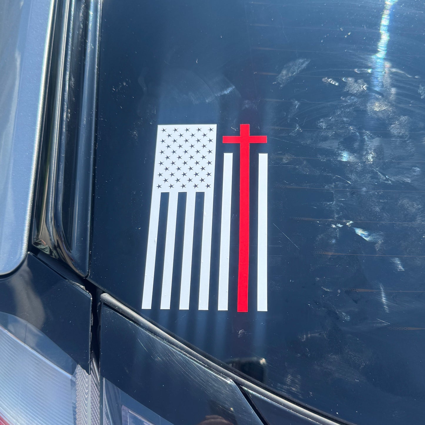 American flag decal with a red cross on a car's black surface