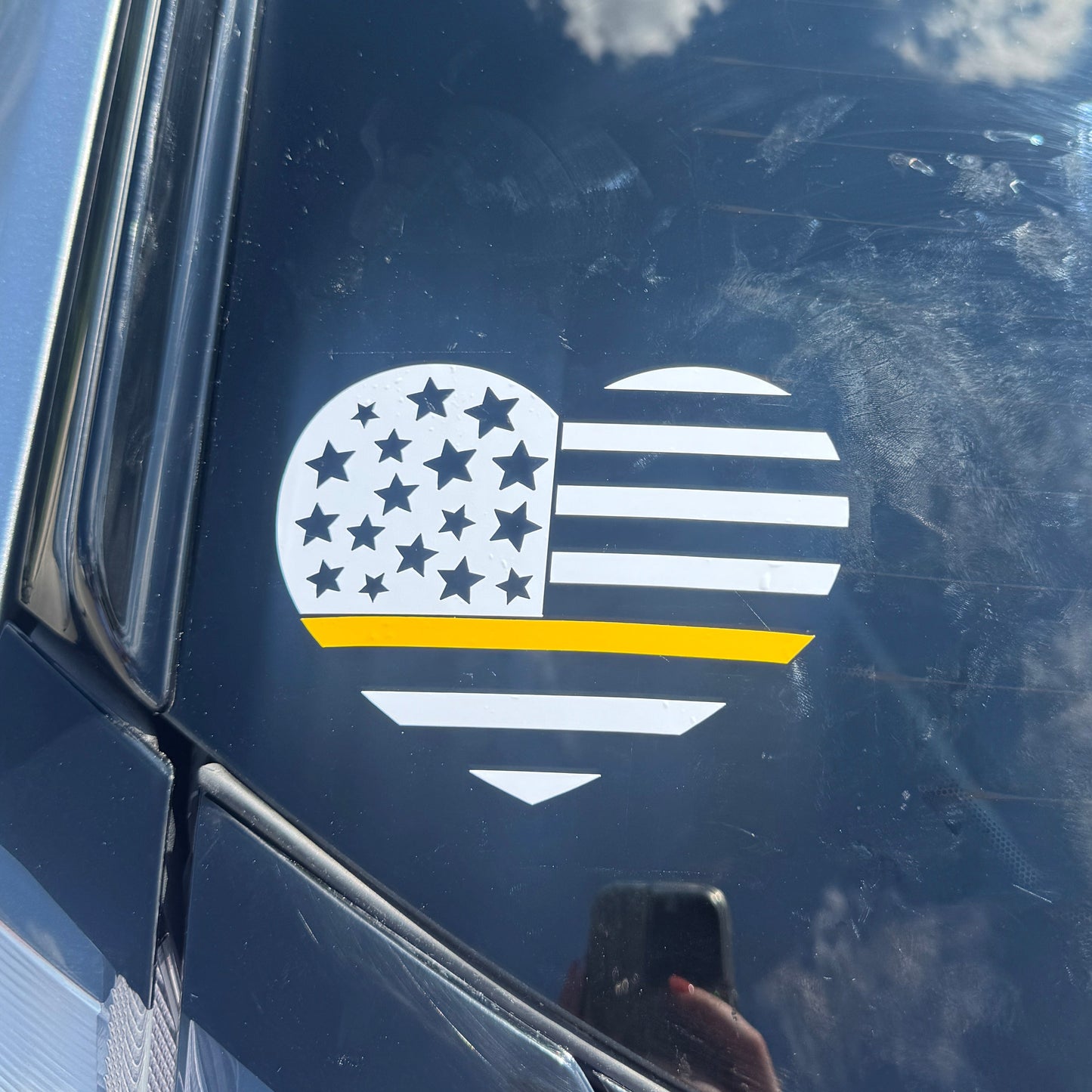 Car window with a decal of a shield with stars and a yellow stripe.