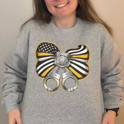 Person wearing a gray sweatshirt with a graphic design of handcuffs and a bow.