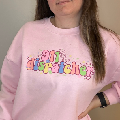 Person wearing a pink sweatshirt with '911 dispatcher' text in colorful letters.