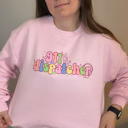 Person wearing a pink sweatshirt with '911 dispatcher' text in colorful letters.