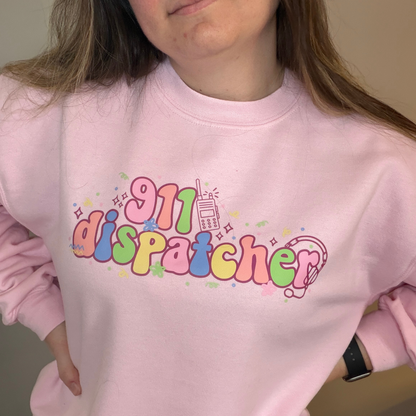 Person wearing a pink sweatshirt with '911 dispatcher' text in colorful letters.