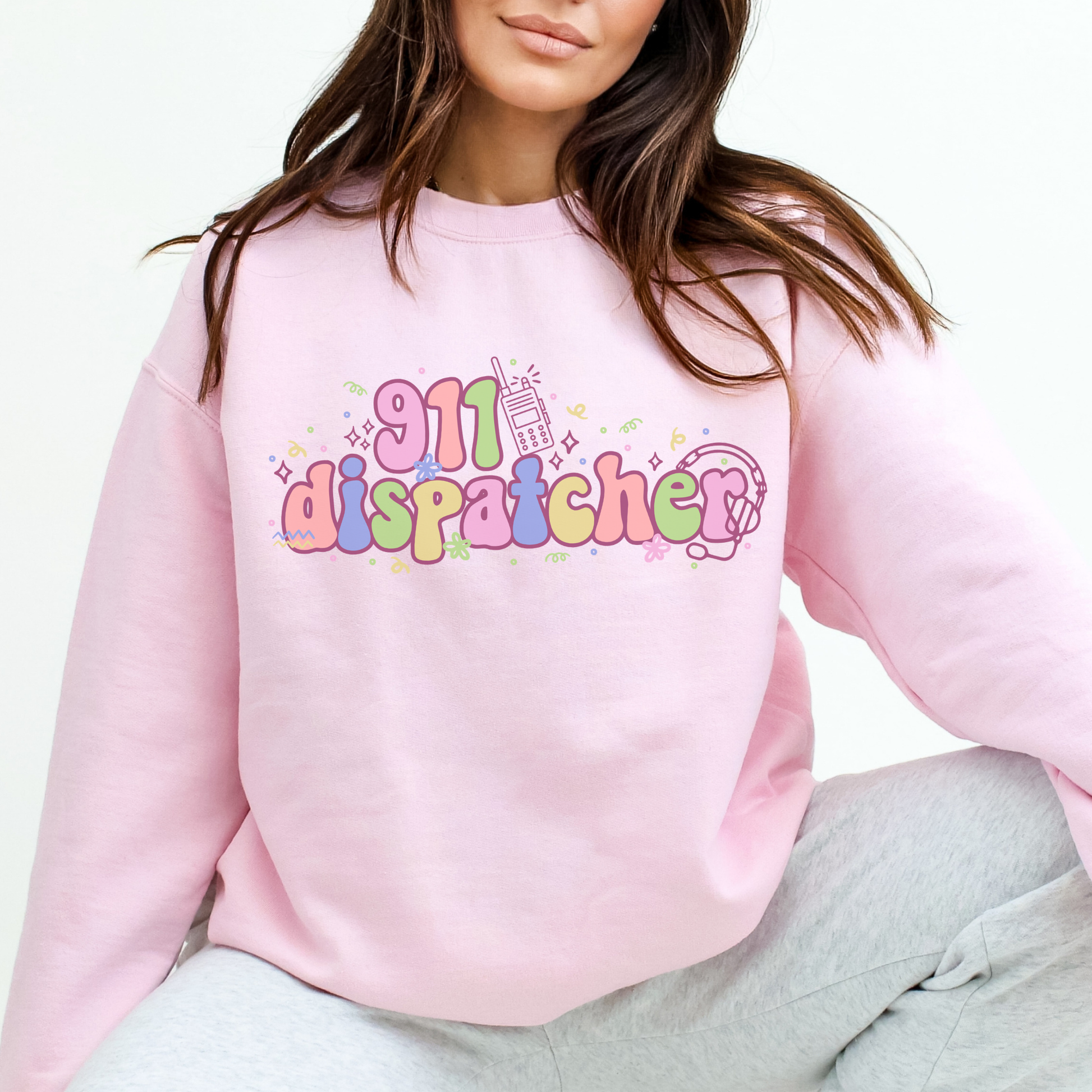 Person wearing a pink sweatshirt with '911 dispatcher' text and graphics.