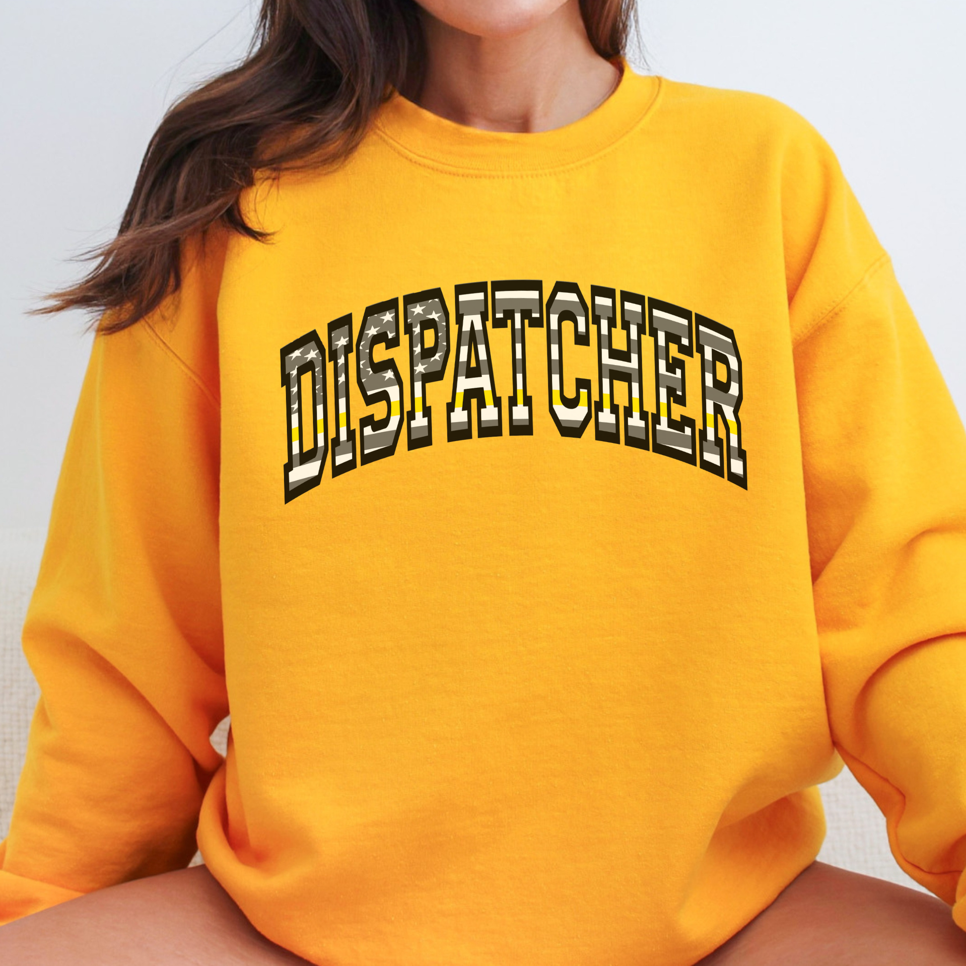 Yellow sweatshirt with 'DISPATCHER' text worn by a person on a plain background