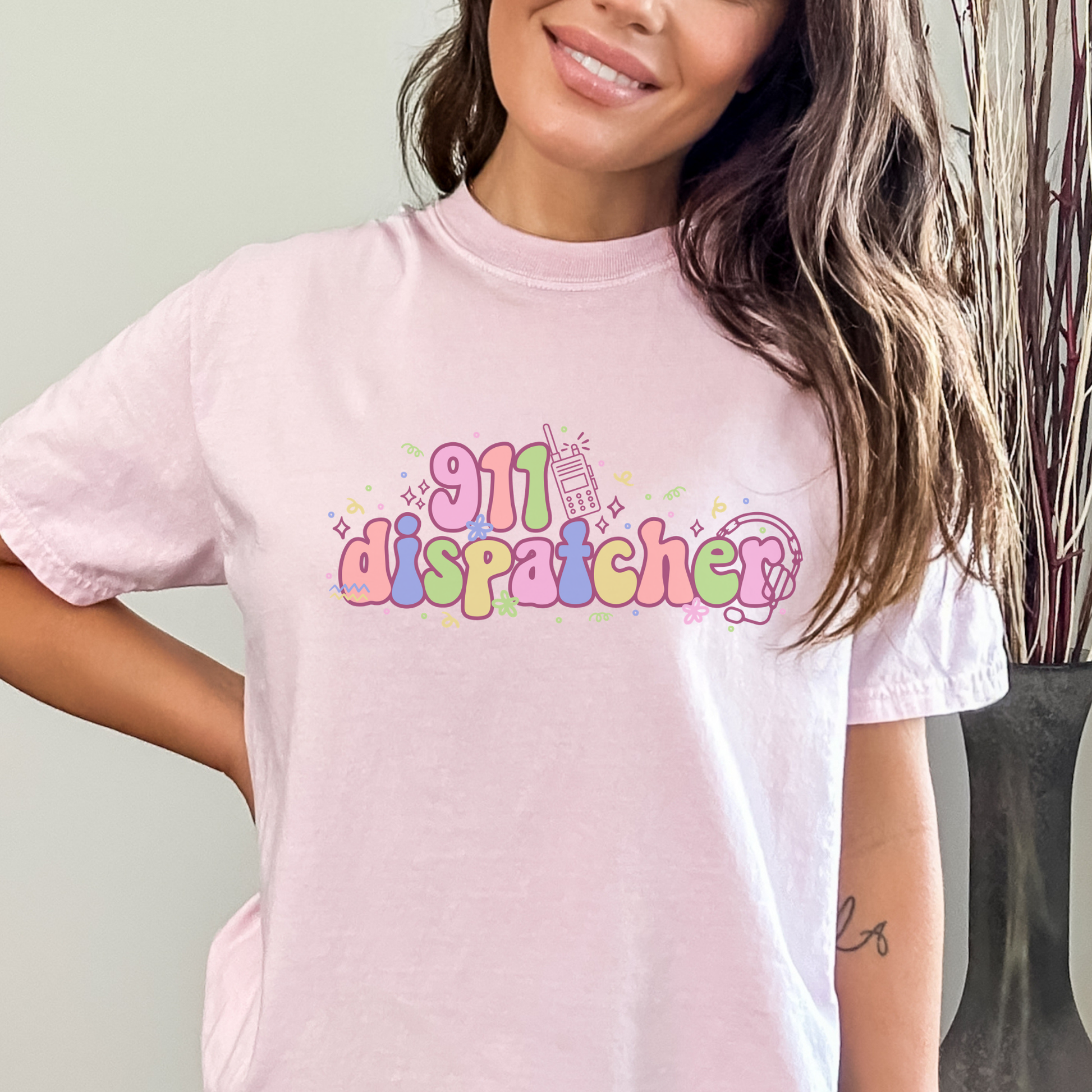 Person wearing a pink t-shirt with '911 dispatcher' text and graphics.