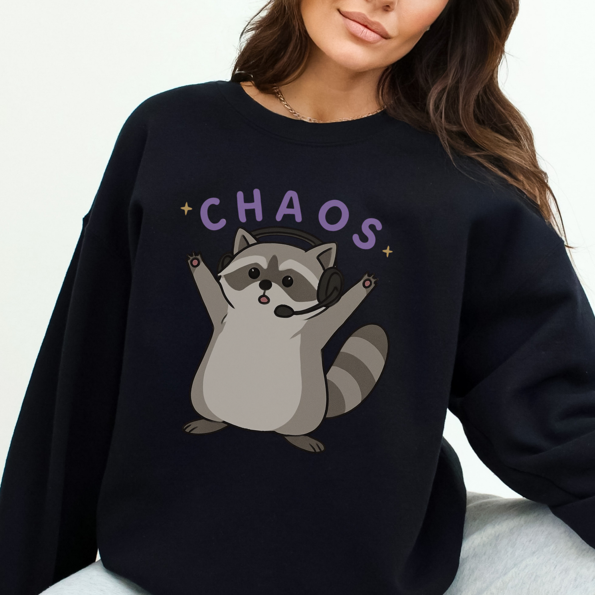 Black sweatshirt with a raccoon graphic and 'CHAOS' text worn by a person.