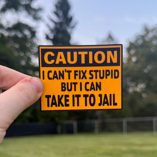 Hand holding a humorous 'Caution' sign with text outdoors.