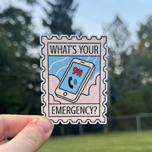 Hand holding a sticker with 'What's Your Emergency?' text against a blurred outdoor background