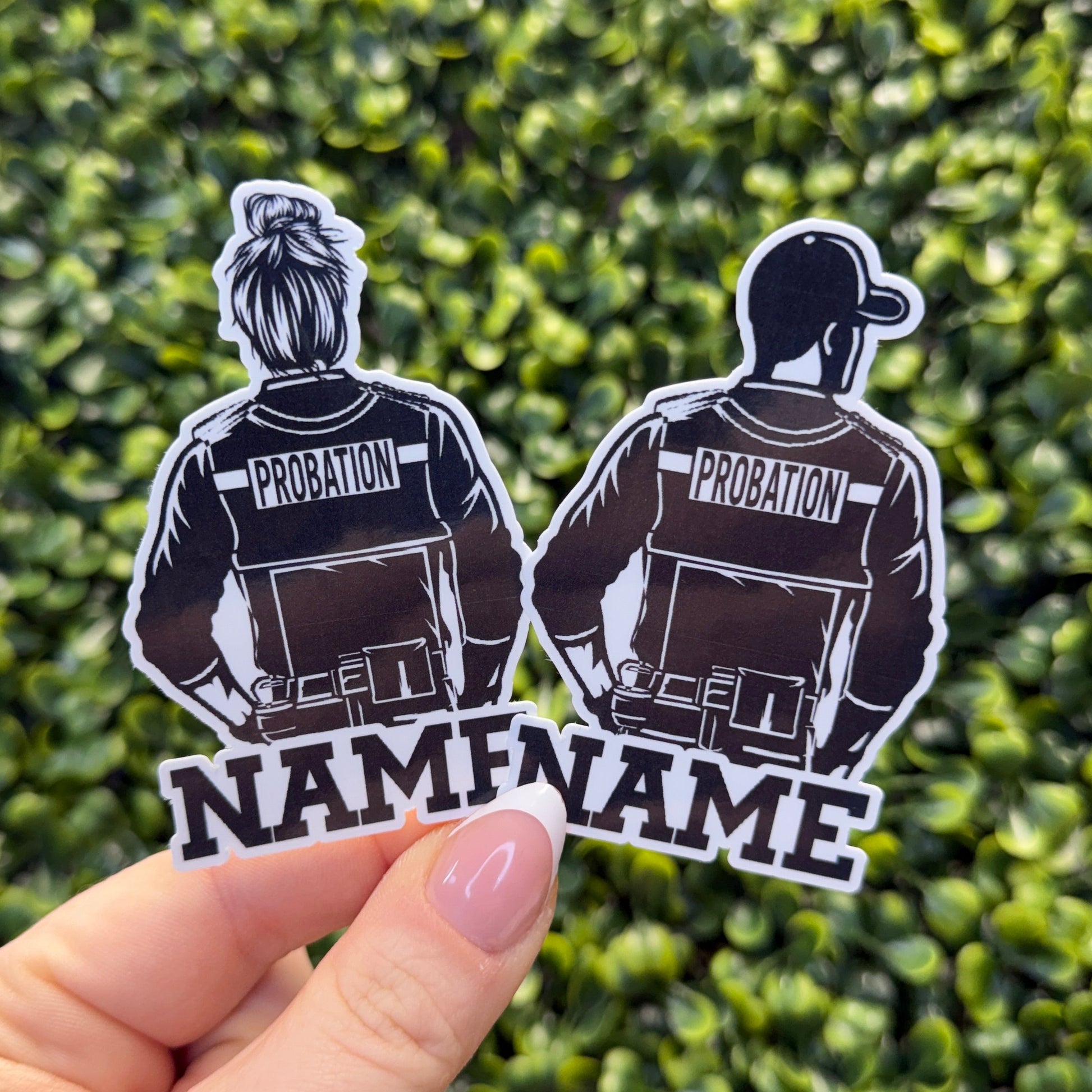 Two black and white stickers of people labeled 'Probation' held against a green leafy background.