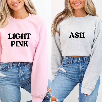 Two women wearing sweatshirts labeled 'Light Pink' and 'Ash' respectively, with blue jeans.